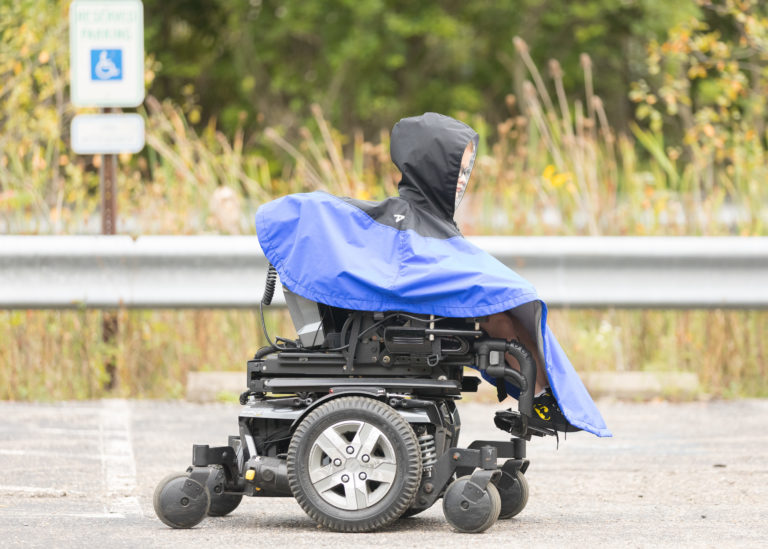 Person wearing a blue Wheely Cape in a wheelchair