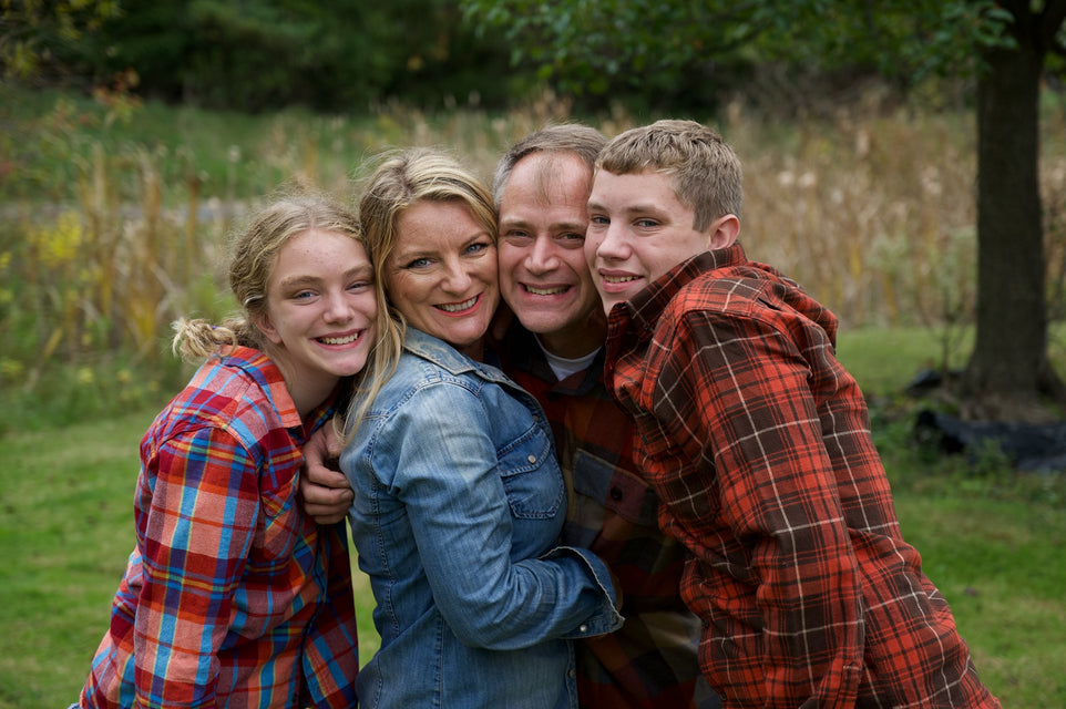 Family dressed in flannel shirts smiling in a family portrait. 